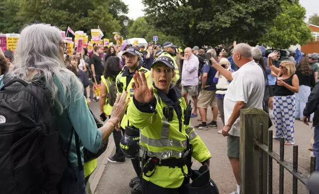 A police officer reacts as demonstrators hold placards and banners as they leave a protest outside the Bell Hotel in Epping, near London, Sunday, July 27, 2025.(AP Photo/Alberto Pezzali)