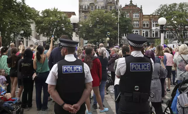 FILE - Police officers watch members of the public outside the Town Hall during a vigil to remember the victims of the stabbing attack last Monday in Southport, England, Monday, Aug. 5, 2024. (AP Photo/Darren Staples, File)