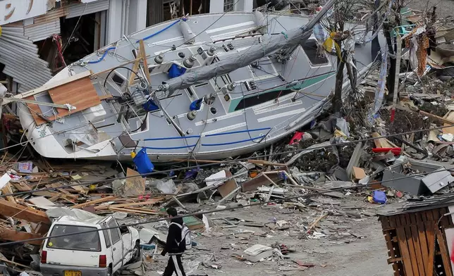 FILE -A man walks near a stranded yacht in the tsunami-hit area in Ofunato, Iwate Prefecture, Japan, March 15, 2011, four days after the disaster. (AP Photo/Itsuo Inouye, File)