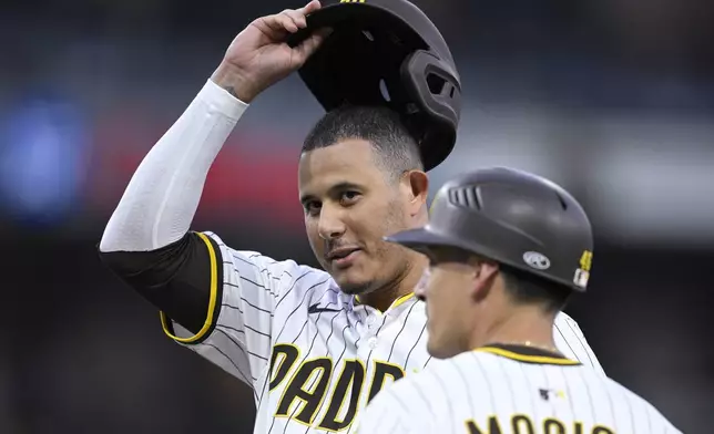San Diego Padres' Manny Machado, left, acknowledges the crowd after hitting a single, his 2000th career hit, during the fourth inning of a baseball game against the Arizona Diamondbacks, Monday, July 7, 2025, in San Diego. (AP Photo/Orlando Ramirez)