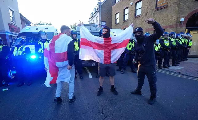 Police officers stand near protesters on Hemnall Street in the town of Epping, after a protest outside the Bell Hotel in Epping, northeast of London, Sunday, July 20, 2025. (Yui Mok/PA via AP)