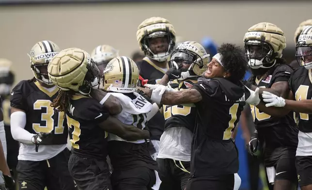 New Orleans Saints cornerback Isaac Yiadom and cornerback Alontae Taylor (1) restrain wide receiver Brandin Cooks (10) during a scuffle with cornerback Rejzohn Wright at an NFL football training camp in Metairie, La., Thursday, July 24, 2025. (AP Photo/Gerald Herbert)