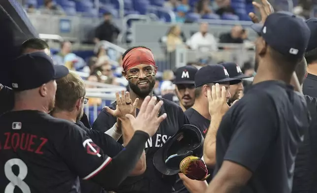 Minnesota Twins' Willi Castro, center, is congratulated in the dugout after scoring on a single hit by Carlos Correa during the fourth inning of a baseball game against the Miami Marlins, Wednesday, July 2, 2025, in Miami. (AP Photo/Lynne Sladky)