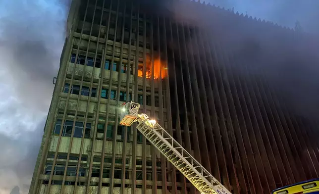 Fire fighters battle flames after a fire broke out in a telecommunications building in central Cairo, Sunday, July 7, 2025. (AP Photo/Ahmed Hatem)
