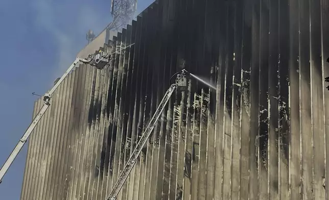 Fire fighters battle flames for the second day after a fire engulfed the main telecom company building in Cairo, Egypt, Tuesday, July 8, 2025, leaving four employees dead and 26 people injured and prompting a temporary outage of internet and mobile phone services, officials said. (AP Photo/Amr Nabil)