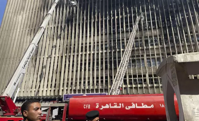 Fire fighters battle flames for the second day after a fire engulfed the main telecom company building in Cairo, Egypt, Tuesday, July 8, 2025, leaving four employees dead and 26 people injured and prompting a temporary outage of internet and mobile phone services, officials said. (AP Photo/Amr Nabil)