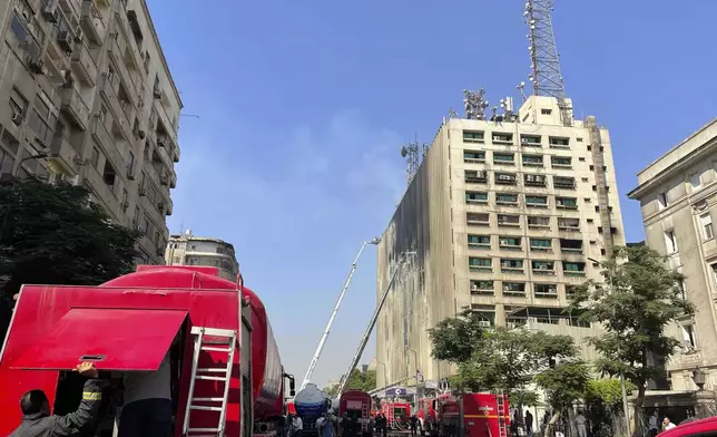 Fire fighters battle flames for the second day after a fire engulfed the main telecom company building in Cairo, Egypt, Tuesday, July 8, 2025, leaving four employees dead and 26 people injured and prompting a temporary outage of internet and mobile phone services, officials said. (AP Photo/Amr Nabil)