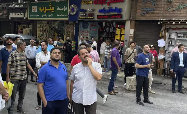 People watch as fire fighters battle flames for the second day after a fire engulfed the main telecom company building in Cairo, Egypt, Tuesday, July 8, 2025, leaving four employees dead and 26 people injured and prompting a temporary outage of internet and mobile phone services, officials said. (AP Photo/Amr Nabil)