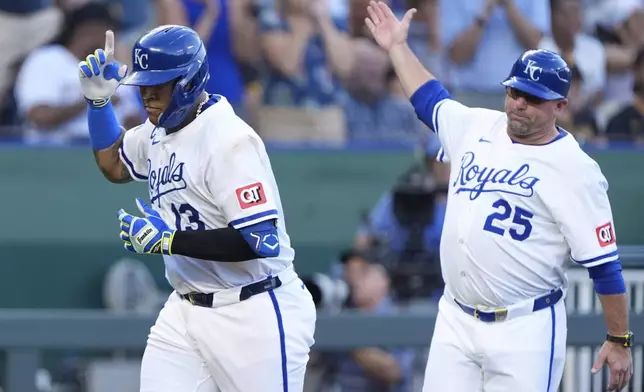 Kansas City Royals' Salvador Perez celebrates with major league field coordinator, third base coach Vance Wilson (25) after hitting a solo home run during the second inning of a baseball game against the Pittsburgh Pirates, Wednesday, July 9, 2025, in Kansas City, Mo. (AP Photo/Charlie Riedel)