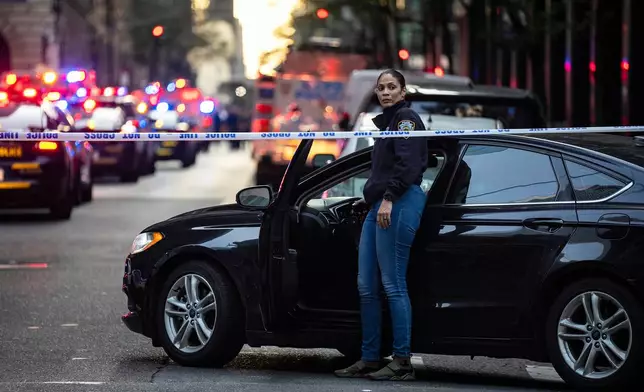 A New York police investigator exits her vehicle at the scene outside a Manhattan office building where two people were shot including a police officer, Monday, July 28, 2025, in New York. (AP Photo/Angelina Katsanis)