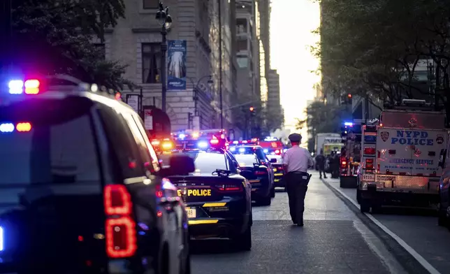A New York police officer stands watch on 52nd Street outside a Manhattan office building where at least two people were shot, including a police officer, Monday, July 28, 2025, in New York. (AP Photo/Angelina Katsanis)