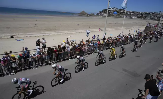 The pack with Netherlands' Mathieu van der Poel wearing the overall leader's yellow jersey rides along the beach during the seventh stage of the Tour de France cycling race over 197 kilometers (122.4 miles) with start in Saint-Malo and finish in Mur-de-Bretagne Guerledan, France, Friday, July 11, 2025. (AP Photo/Mosa'ab Elshamy)