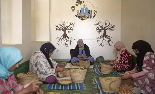 Women crack argan nuts at a cooperative that extracts and produces argan oil and products, in Essaouira, Morocco, Thursday, May 22, 2025. (AP Photo/Mosa'ab Elshamy)