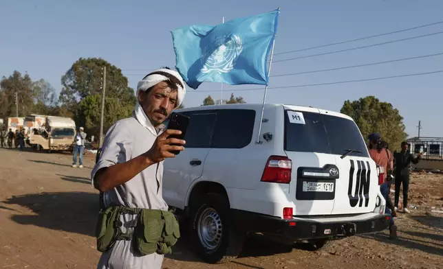 A Bedouin fighter takes a selfie in front of a U.N. vehicle as a convoy of ambulances and buses arrives at a checkpoint in the village of Busra al-Harir, southern Syria, on its way to Sweida province, as security forces cordon off the area to block Bedouin fighters from entering the province, Tuesday, July 22, 2025. (AP Photo/Omar Sanadiki)