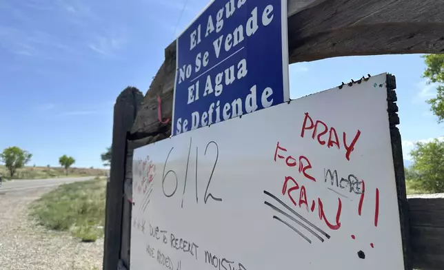 A sign posted along a traditional irrigation canal known as an acequia requests that passersby pray for rain as the monsoon gets under way near Española, New Mexico, on June 13, 2025. (AP Photo/Susan Montoya Bryan)