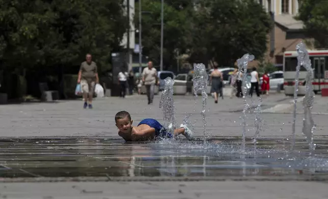 A boy plays in a fountain during hot weather in Kosovo's capital Pristina on Thursday, July 3, 2025. (AP Photo/Visar Kryeziu)