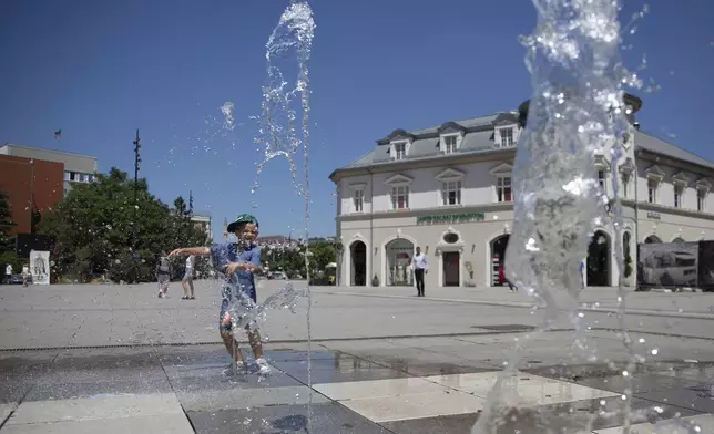 A boy plays in a fountain during hot weather in Kosovo's capital Pristina on Thursday, July 3, 2025. (AP Photo/Visar Kryeziu)