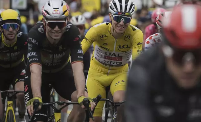 A smiling Tadej Pogacar of Slovenia, wearing the overall leader's yellow jersey, crosses the finish line with Belgium's Wout van Aert, second left, and Britain's Simon Yates, far left, during the twentieth stage of the Tour de France cycling race over 184.2 kilometers (114.5 miles) with start in Nantua and finish in Pontarlier, France, Saturday, July 26, 2025. (AP Photo/Thibault Camus)