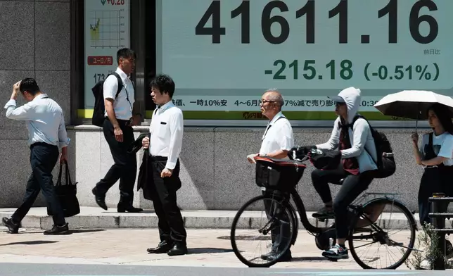 People stand in front of an electronic stock board showing Japan's Nikkei index at a securities firm Friday, July 25, 2025, in Tokyo. (AP Photo/Eugene Hoshiko)