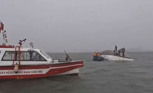 This image from a video provided by QDND shows people on a capsized tourist boat being rescued in Ha Long Bay, Vietnam on Saturday, July 19, 2025. (QDND via AP)
