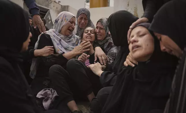 Lian Al-Za'anin, center, is comforted by relatives as she mourns the loss of her father, Rami Al-Za'anin, who was killed while heading to an aid distribution hub, at the morgue of the Shifa Hospital in Gaza City, on Thursday, July 3, 2025. (AP Photo/Jehad Alshrafi)