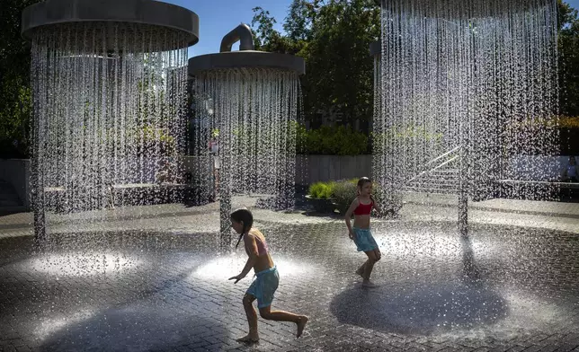 Children cool off on a hot day in a public fountain in Vilnius, Lithuania, Thursday, July 3, 2025. (AP Photo/Mindaugas Kulbis)