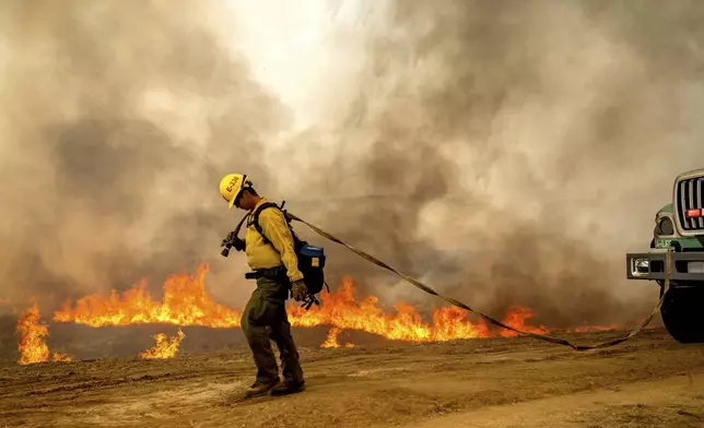 U.S. Forest Service firefighter Kai Montes battles the Madre Fire as it makes a run along Highway 166 on Thursday, July 3, 2025, in San Luis Obispo County, Calif. (AP Photo/Noah Berger)