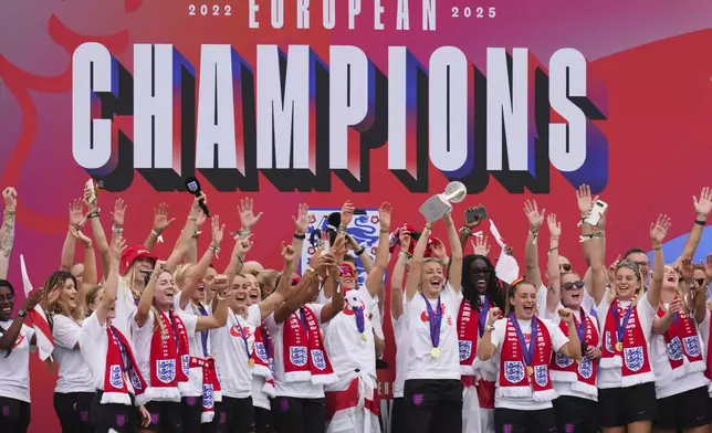 England's soccer team captain Leah Williamson lifts the trophy with her teammates on a stage celebrating with thousands of fans during a homecoming victory parade and celebration outside Buckingham Palace in London, after winning the Women's Euro 2025,Tuesday, July 29, 2025.(AP Photo/Kirsty Wigglesworth)