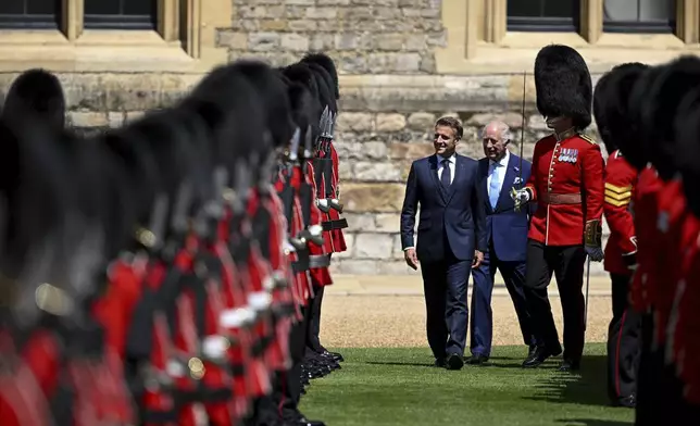 Britain's King Charles III and French President Emmanuel Macron, left, review the Guard of Honour at Windsor Castle as part of a welcome ceremony for the French President and his wife Brigitte Macron, in Windsor, England, Tuesday July 8, 2025, on the first day of a three-day state visit to Britain. (Dylan Martinez/Pool via AP)