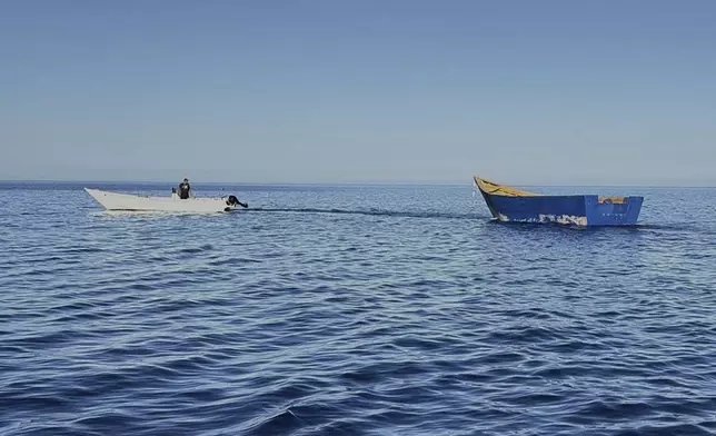A boat used by migrants to cross the Mediterranean Sea is towed from Tripiti beach to the Karave the port of Gavdos, Greece, on Monday, July 7, 2025 after hundreds were rescued near the island and the island of Crete in separate incidents. (AP Photo/Elena Becatoros)