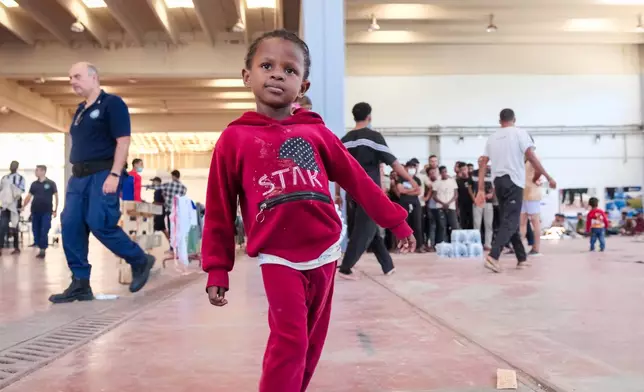 A child looks on as other migrants take shelter in Agia port, Chania, Crete island, Greece, Monday, July 7, 2025. (AP Photo/Giannis Angelakis)