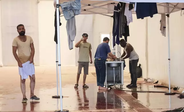 Migrants from Africa wash their clothes as they take shelter in Agia port, Chania, Crete island, Greece, Monday, July 7, 2025. (AP Photo/Giannis Angelakis)