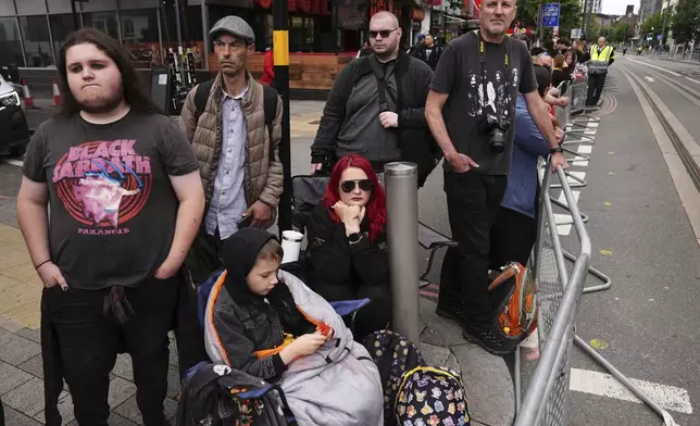 Fans gather near the Black Sabbath Bridge bench on Broad Street ahead of the funeral procession for Black Sabbath frontman Ozzy Osbourne, in Birmingham, England, Wednesday July 30, 2025. (Jacob King/PA via AP)