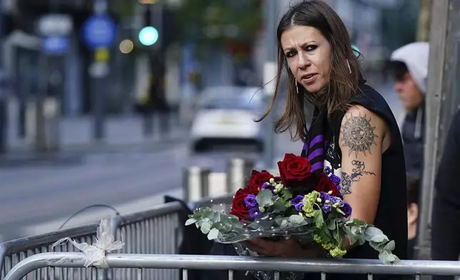 A fan waits near the Black Sabbath Bridge bench on Broad Street ahead of the funeral procession for Black Sabbath frontman Ozzy Osbourne, in Birmingham, England, Wednesday July 30, 2025. (Jacob King/PA via AP)
