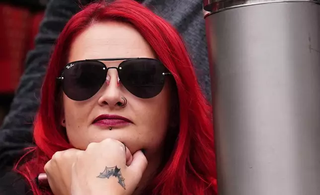 A fan waits near the Black Sabbath Bridge bench on Broad Street ahead of the funeral procession for Black Sabbath frontman Ozzy Osbourne, in Birmingham, England, Wednesday July 30, 2025. (Jacob King/PA via AP)