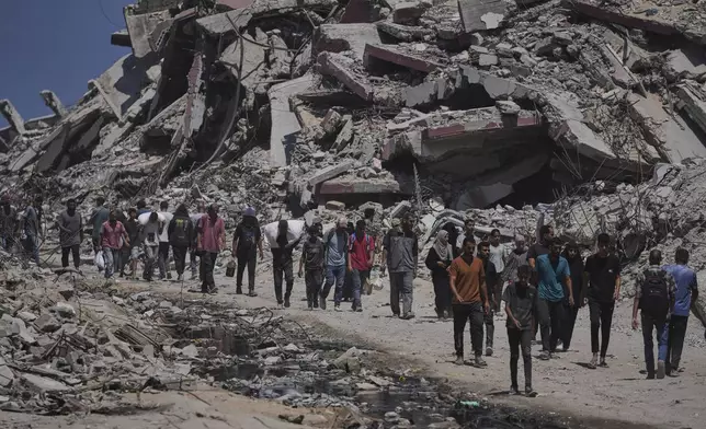 Palestinians carry sacks of humanitarian aid unloaded from trucks convoy that had been heading to Gaza City, in the northern Gaza Strip Sunday, July 20, 2025. (AP Photo/Jehad Alshrafi)