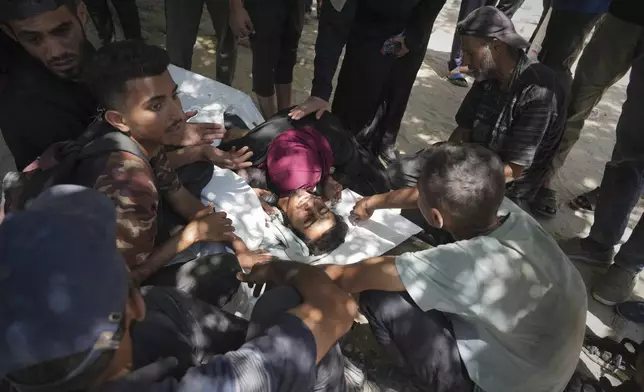 Palestinians mourn over the body of Ezzedine Qassem who was killed while attempting to access aid trucks entering northern Gaza through the Zikim crossing with Israel, at a clinic in Gaza City, Sunday, July 20, 2025. (AP Photo/Jehad Alshrafi)