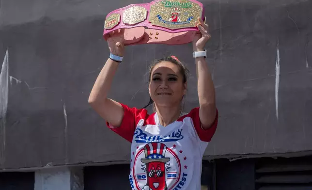 Competitive eater Miki Sudo raises a champion belt as she arrives at the 2025 Nathan's Famous Fourth of July hot dog eating contest in the Coney Island section of the Brooklyn borough of New York, Thursday, July 4, 2025. (AP Photo/Yuki Iwamura)