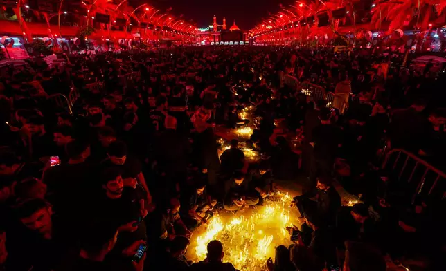 Shiite faithful pilgrims light candles outside the Imam Hussein shrine, seen in the background, during a Muharram procession marking Ashoura, to commemorate the martyrdom of Imam Hussein, grandson of the Prophet Muhammad, in Karbala, Iraq, Sunday, July 6, 2025. (AP Photo/Anmar Khalil)