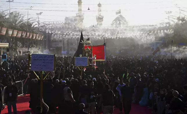 Shiite faithful worshippers gather between the holy shrines of Imam Hussein and Imam Abbas, in the background, during Muharram, a period of mourning for Shiites, in Karbala, Iraq, Saturday, July. 5, 2025. (AP Photo/Anmar Khalil)