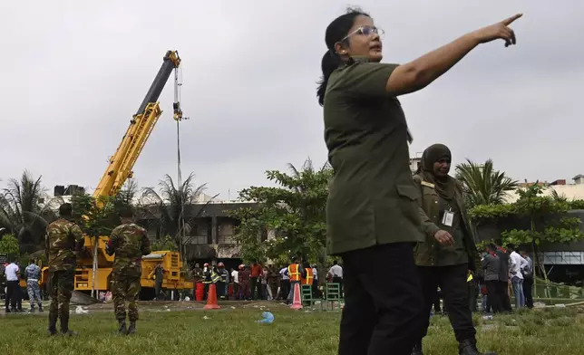 Police officials and firemen work at the site after a Bangladesh Air Force training aircraft crashed onto a school campus shortly after takeoff in Dhaka, Bangladesh, Monday, July 21, 2025. (AP Photo/Mahmud Hossain Opu)