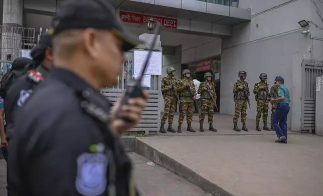 Law enforcement officers stand guard at the entrance of the National Institute of Burn and Plastic Surgery as survivors are treated inside after a Bangladesh air force training aircraft crashed into a school in the nation's capital Monday afternoon in Dhaka, Bangladesh, Tuesday, July 22, 2025.( AP Photo/ Mahmud Hossain Opu)