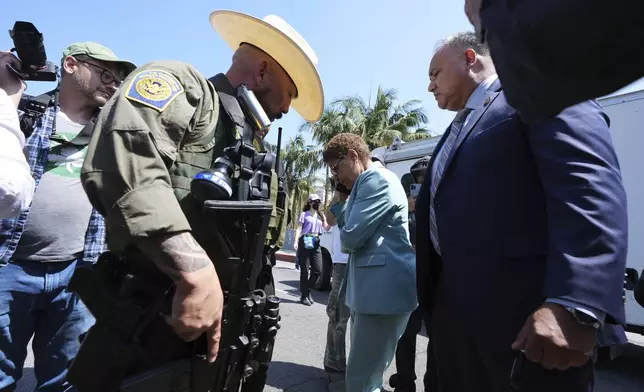 Los Angeles Mayor Karen Bass talks on her mobile phone next to a border patrol federal agent at MacArthur Park Monday, July 7, 2025, in Los Angeles. (AP Photo/Damian Dovarganes)