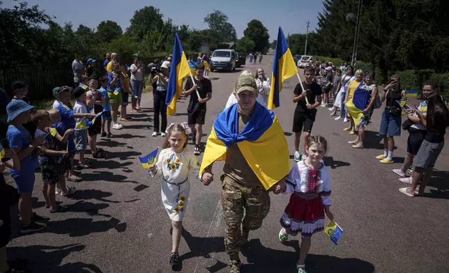 Ukrainian soldier Denys Zalizko, 21, walks though his fellow villagers after returning from Russian captivity in Holovyno, Zhytomyr region, Ukraine, Monday, July 7, 2025. (AP Photo/Evgeniy Maloletka)