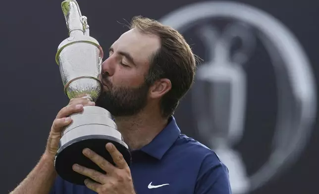 Scottie Scheffler of the United States kisses the Claret Jug trophy as he poses for photographers after winning the British Open golf championship at the Royal Portrush Golf Club, Northern Ireland, Sunday, July 20, 2025. (AP Photo/Jon Super)