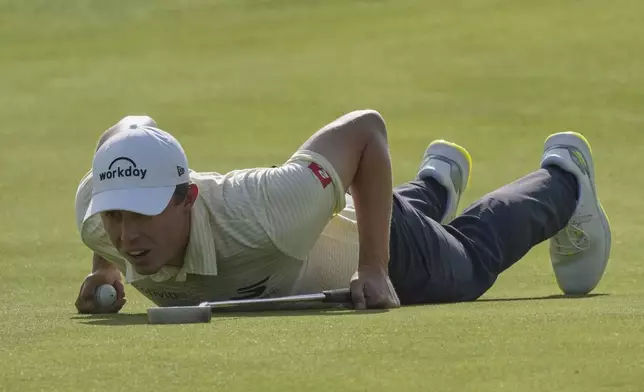 Matt Fitzpatrick of England looks at the lie of his putt by laying down on the 10th green during the third round of the British Open golf championship at the Royal Portrush Golf Club, Northern Ireland, Saturday, July 19, 2025. (AP Photo/Jon Super)