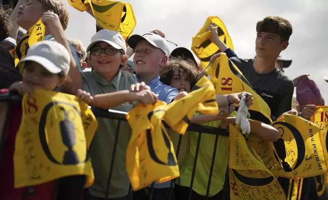 Children smile as they wait for Rory McIlroy of Northern Ireland with replica 18th hole pin flags to be signed during a practice round for the British Open golf championship at the Royal Portrush Golf Club, Northern Ireland, Wednesday, July 16, 2025. (AP Photo/Francisco Seco)