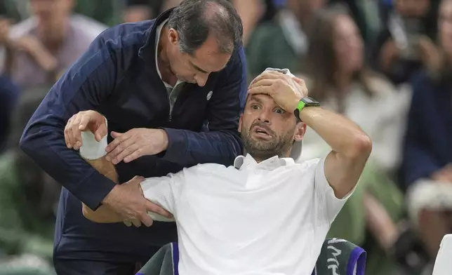 Bulgaria's Grigor Dimitrov gets treatment after he went down with an injury which forced him to retire injured from a fourth round men's singles match against Italy's Jannik Sinner at the Wimbledon Tennis Championships in London, Monday, July 7, 2025. (AP Photo/Kin Cheung)