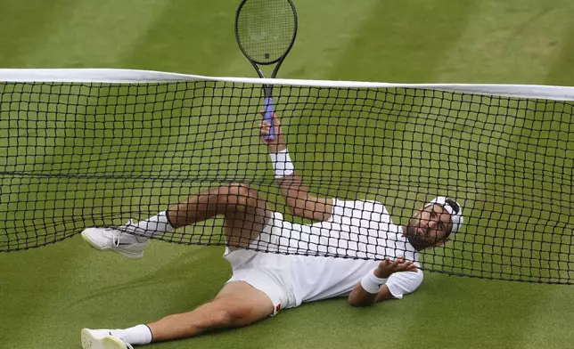 Karen Khachanov of Russia slides under the netting during his men's singles fourth round match against Kamil Majchrzak of Poland at the Wimbledon Tennis Championships in London, Sunday, July 6, 2025.(AP Photo/Kirsty Wigglesworth)