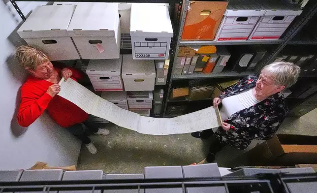 Historian Jennifer Cromack, left, and Rev. Diane Badger unfurl a recently found, 178-year-old anti-slavery scroll which was found in a storage box at Grotonwood, the home mission of The American Baptist Churches of Massachusetts, Thursday, June 26, 2025, in Groton, Mass. (AP Photo/Charles Krupa)